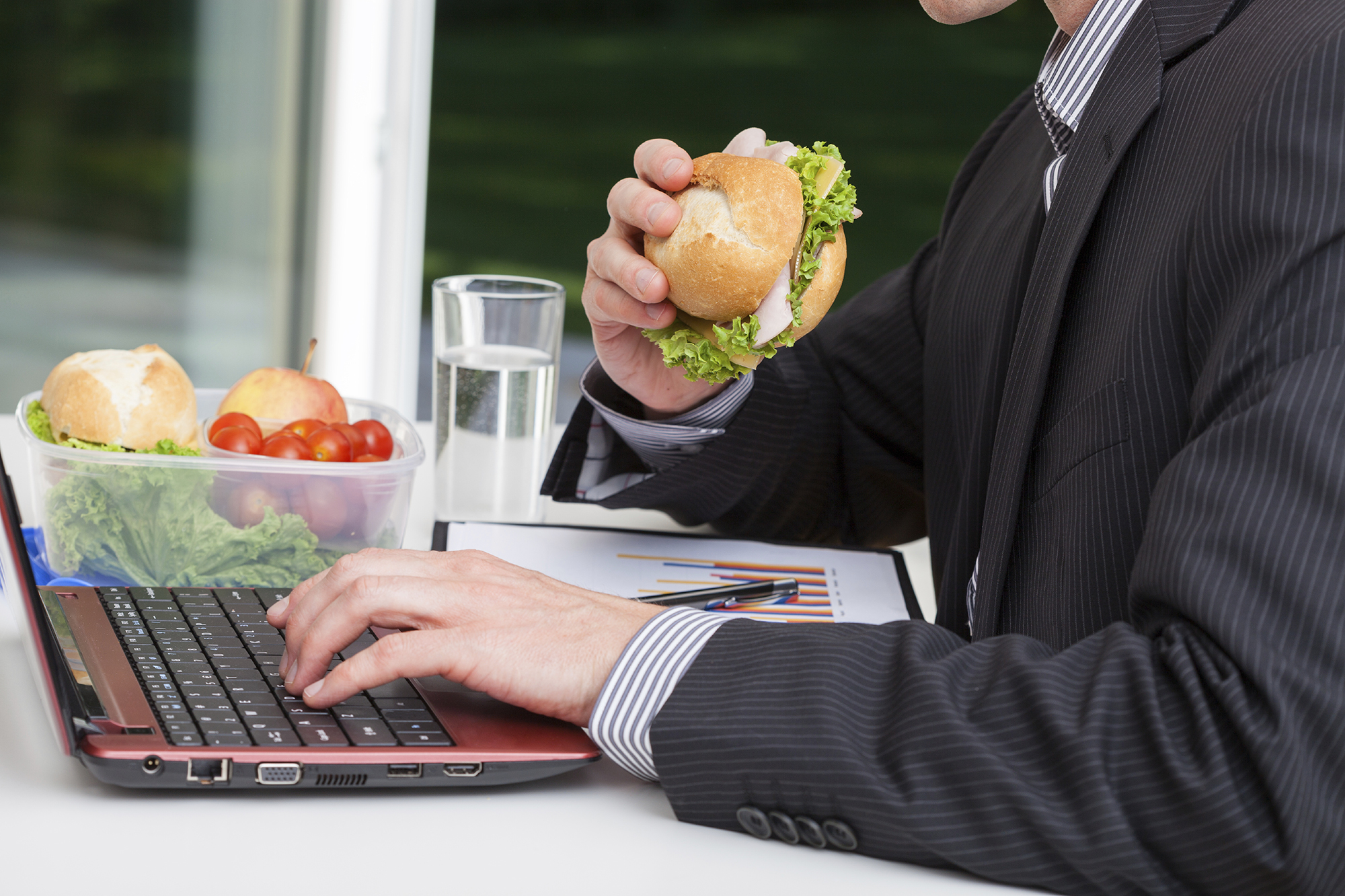 Worker in office eating healthy sandwich at his desk