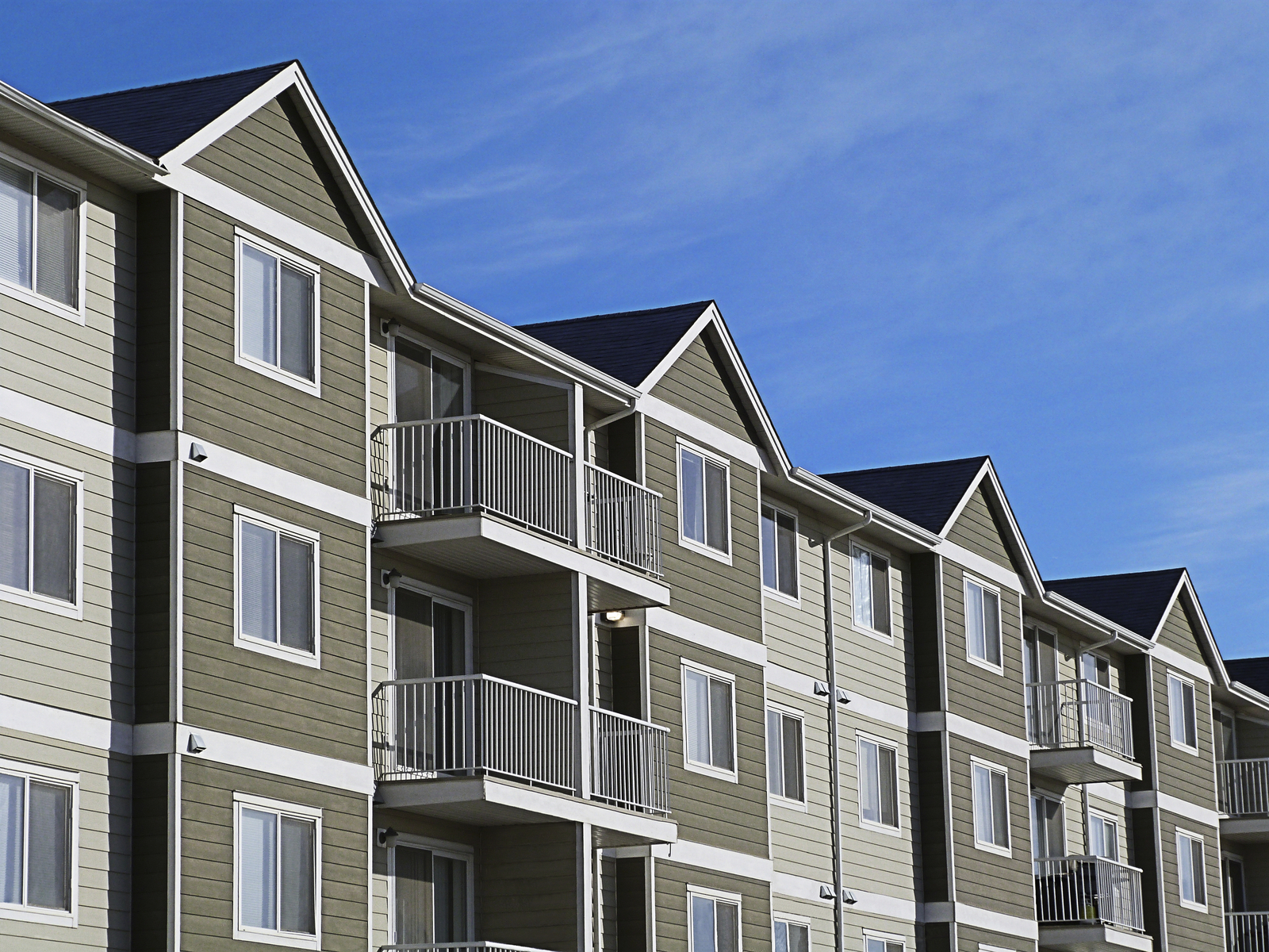 A row of a modern apartment complex development with a bright blue sky.