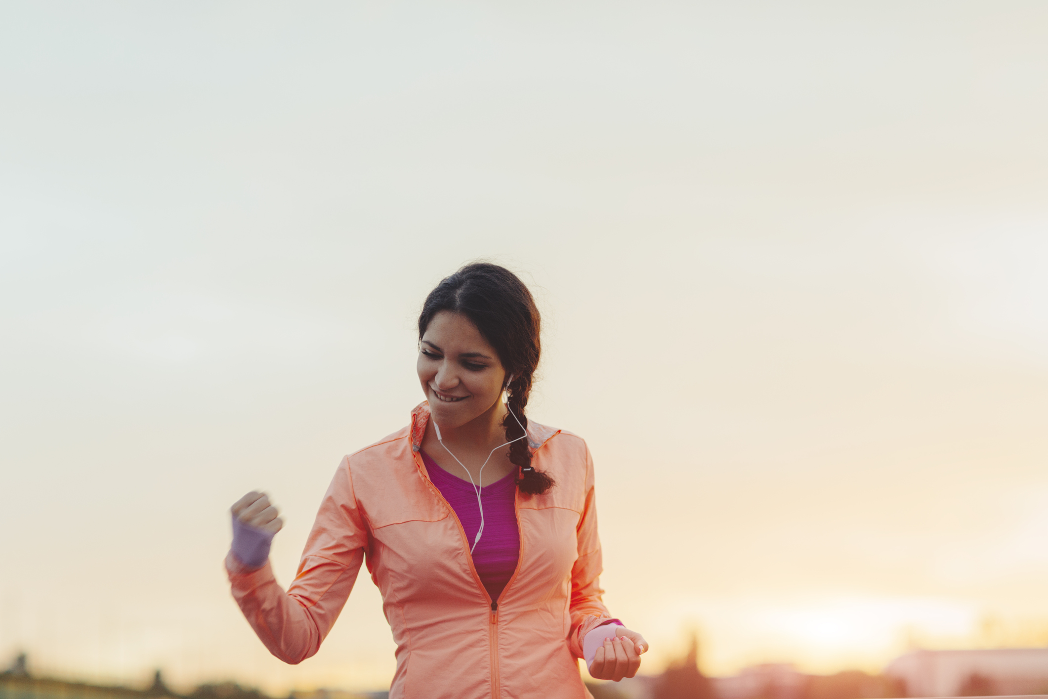 Female Runner Jogging in the city and finishing her training with her hand up in the air screaming with happiness. She made her goal!